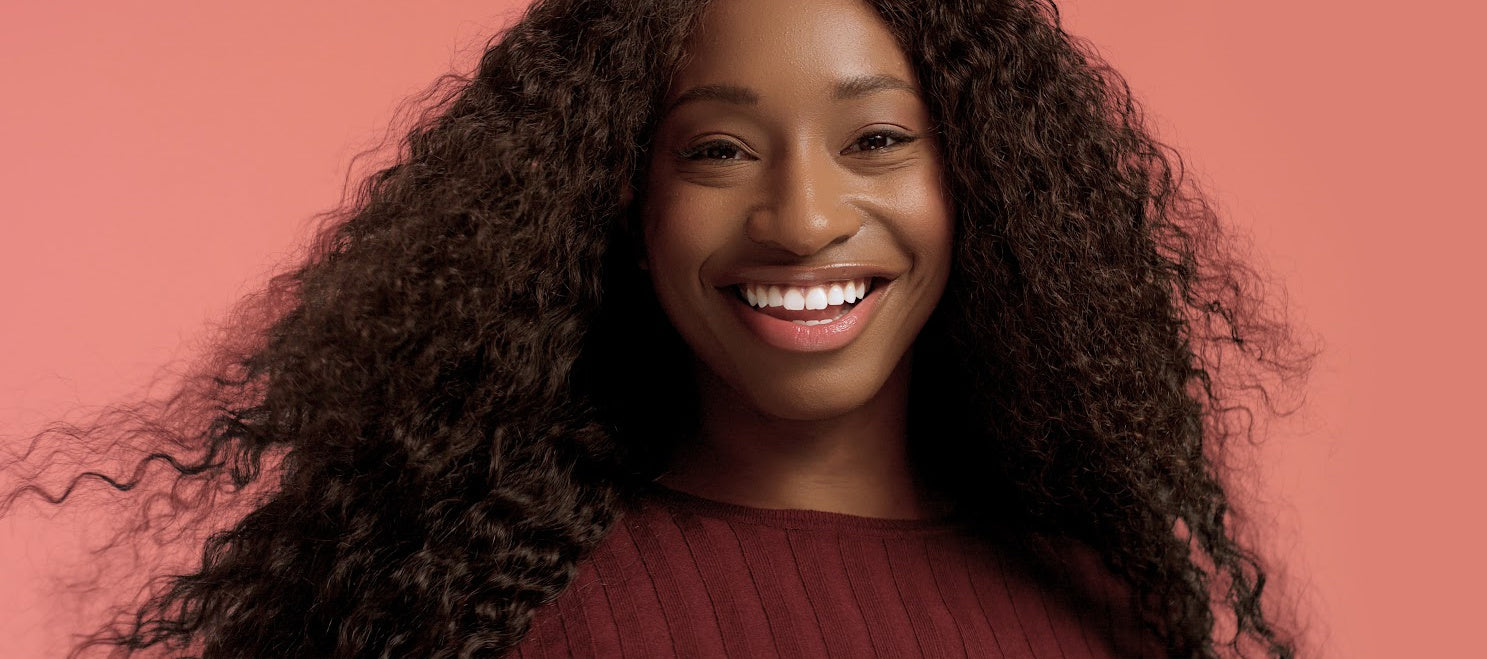 Smiling Black woman with flawless microlink hair extensions made from 100% virgin human hair, showcasing natural texture and seamless volume.