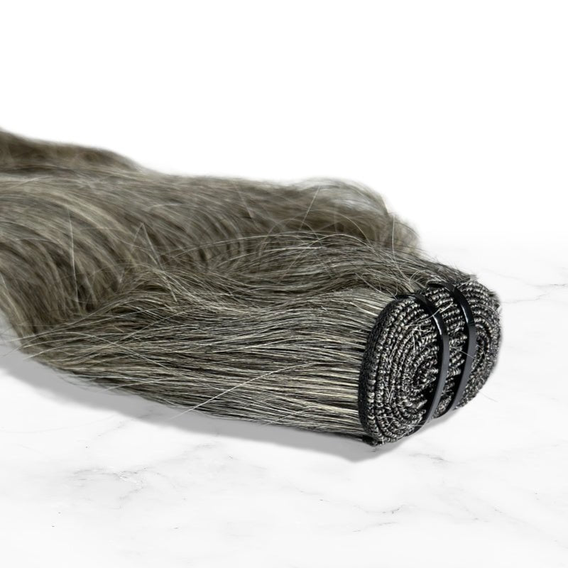 Displayed is a Up close shot of SL Raw Virgin Hair Salt and Pepper gray hair vietnamese human hair bundles with a slight wave. beautiful hair wefts for a perfect sew in or pronto weave