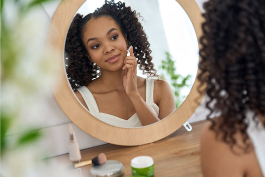 Woman in the mirror with clear skin wearing hair extensions with proper care - SL Raw Virgin Hair 