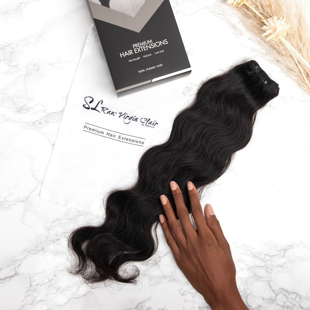 A women hand touching raw wavy human hair bundle extensions by SL Raw Virgin Hair 