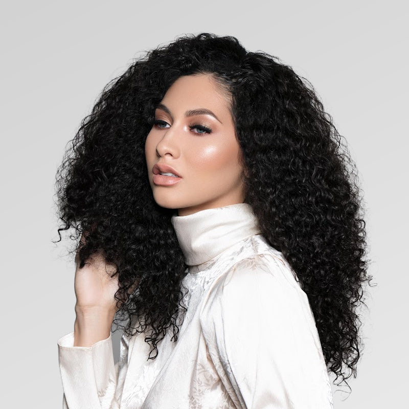 Image of Biracial Woman wearing SL Raw Burmese Curly Hair extensions in length 16-inches. Hair type 3a-3b. hair color #1b. Hair wefts sold 3.3oz per pack.