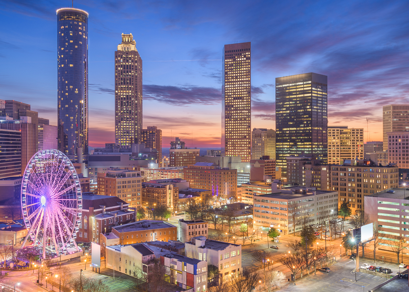 Atlanta City skyline with tall buildings and a Ferris wheel at dusk.