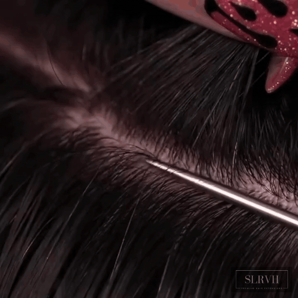 Hairstylist parting hair and weaving around a premium human hair bundle weft during a quick sew-in installation.
