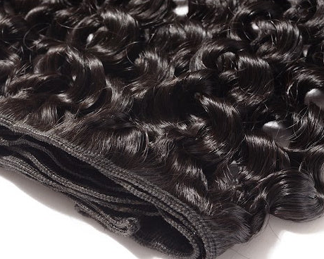 A close-up of dark, curly hair weft extensions with a black mesh base, shown on a plain white background.