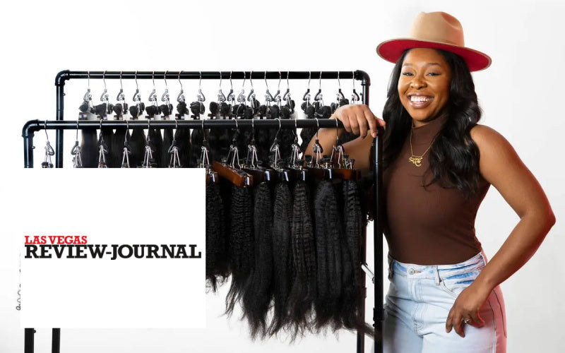 Owner of SL Raw Virgin Hair standing next to a rack of hair extensions with 'Las Vegas Review Journal' branding.