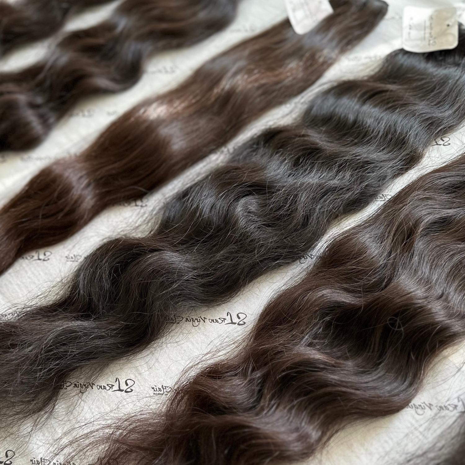 Raw hair bundles of indian wavy hair extensions on a textured surface.