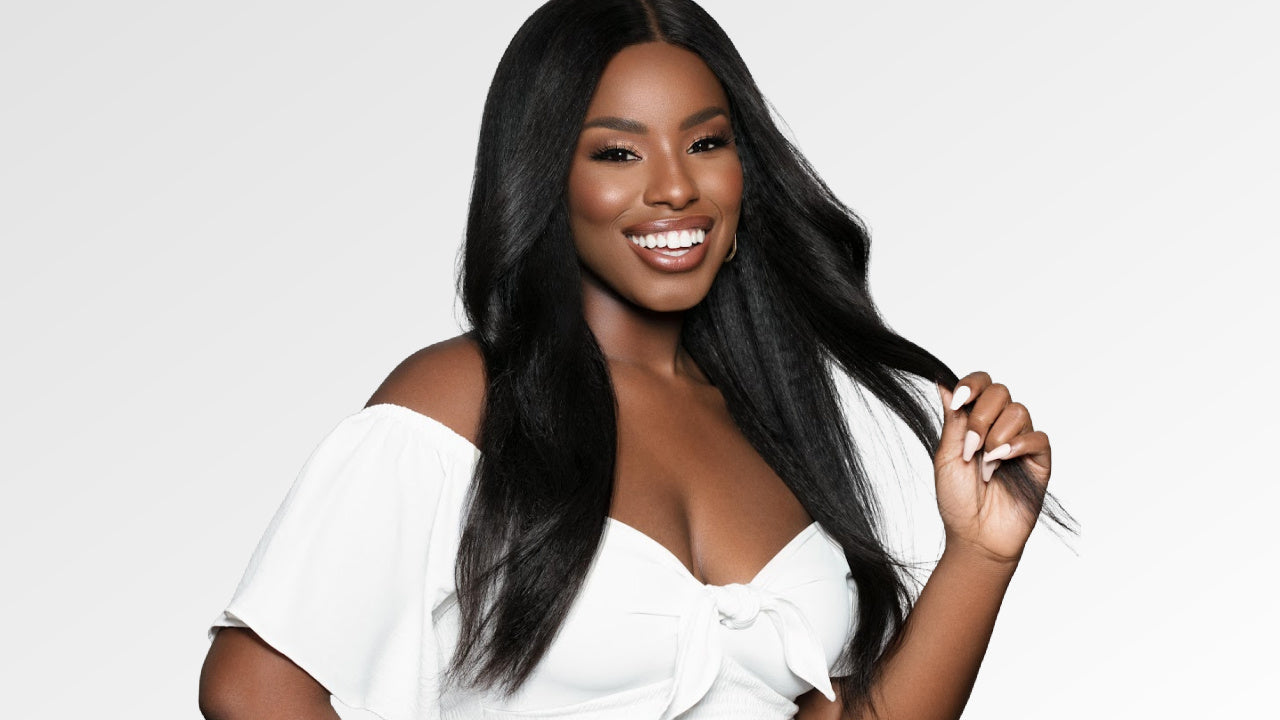 Smiling woman wearing kinky straight hair extensions, styled in a flowing, natural look, perfectly blending with her African American hair texture. by SL Raw Virgin Hair 