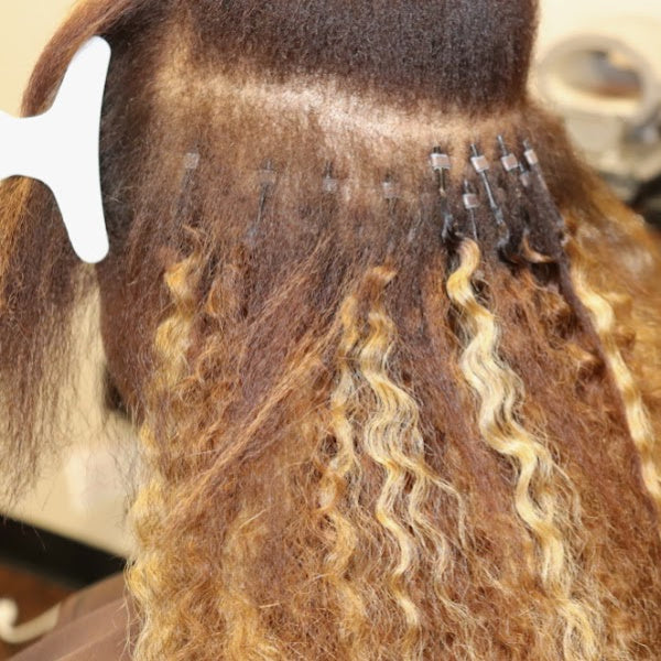 Close-up of a microlink hair extension being applied to a person's head.