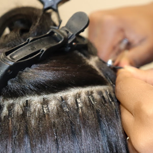 Close-up of a microlink hair extension being worked on.