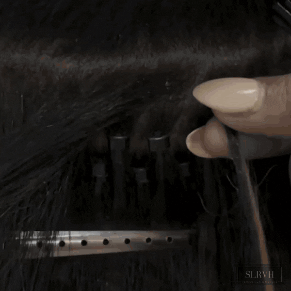 Close-up of a hairstylist attaching a microbead to a microlink I-tip hair extension, demonstrating the professional installation process.