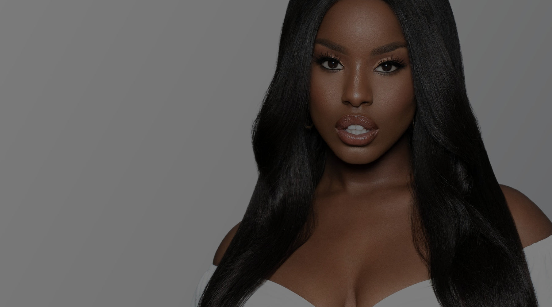 Woman with long black hair against a gray background