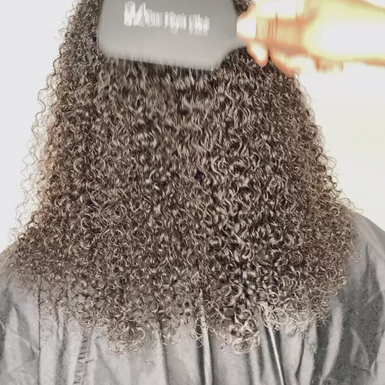 Hand using SL Raw Virgin Hair® detangling brush on kinky curly human hair extensions to demonstrate gentle maintenance and texture definition.