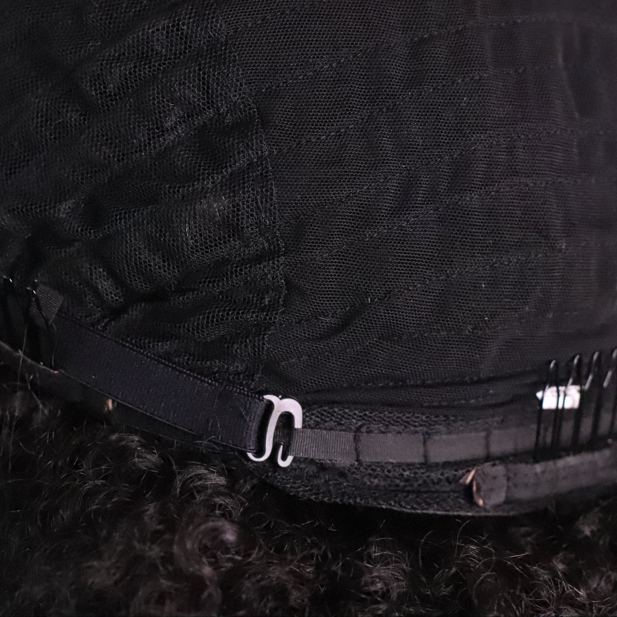 Inside view of Soft Kinky Curly lace front wig showing black mesh cap construction, interior combs and adjustable strap
